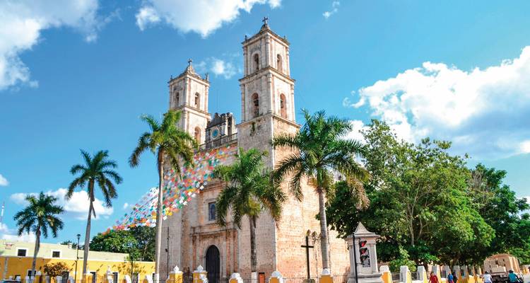 Cathédrale avec tours jumelles et bannières colorées devant.