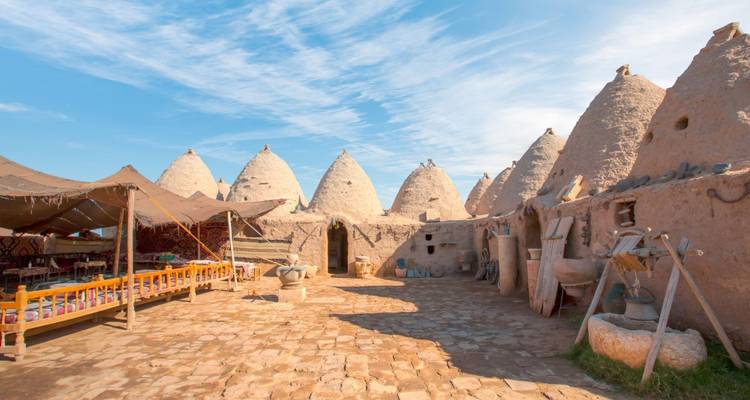 Traditional beehive houses under a blue sky.
