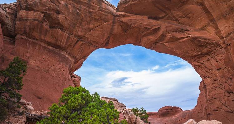 Arche de grès rouge naturel encadrant un ciel bleu et la végétation du désert dans le parc national des Arches