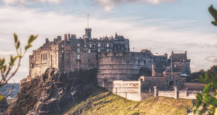 Edinburgh Castle sits atop rugged volcanic rock overlooking the city under a dramatic sky.