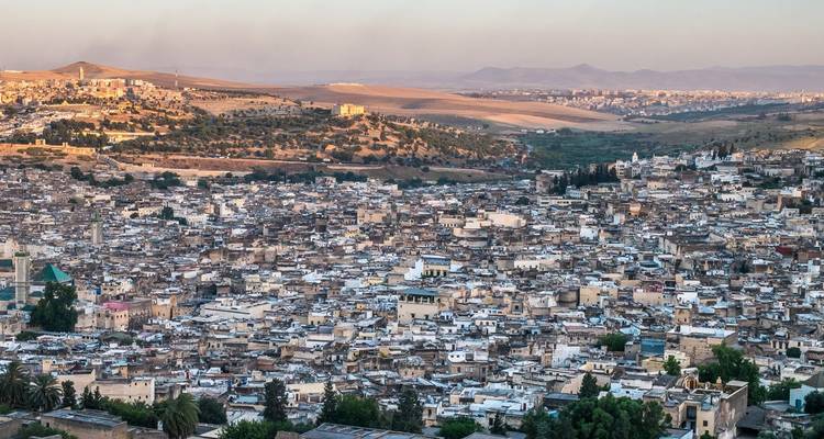 Dusk panorama across the sprawling medina of Fes fading into rolling countryside.