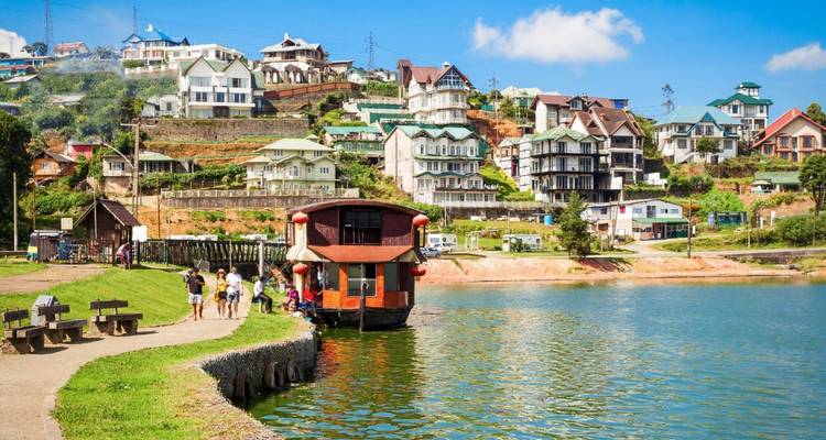 Colorful hillside town overlooking a tranquil lake with tourists walking along the shore