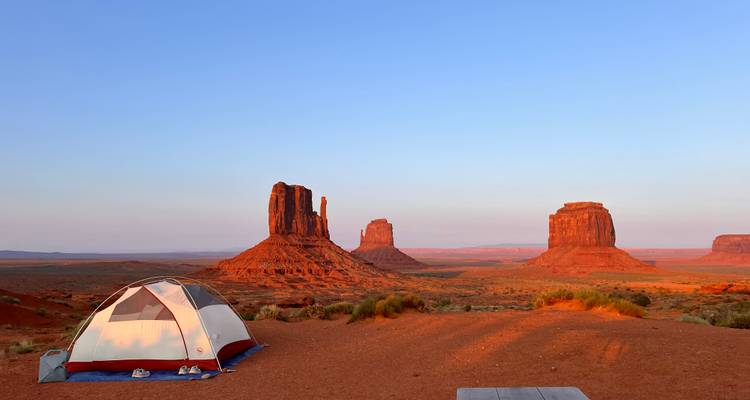Vue panoramique de Monument Valley avec une tente au premier plan.