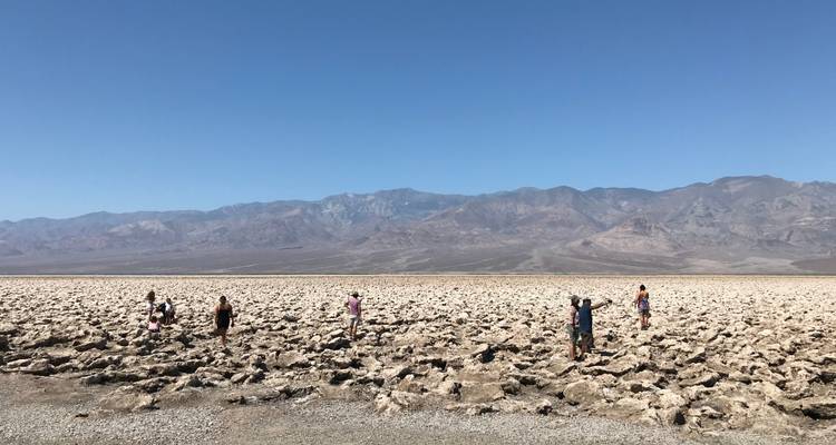 Grupo de personas explorando un paisaje desértico rocoso con montañas.