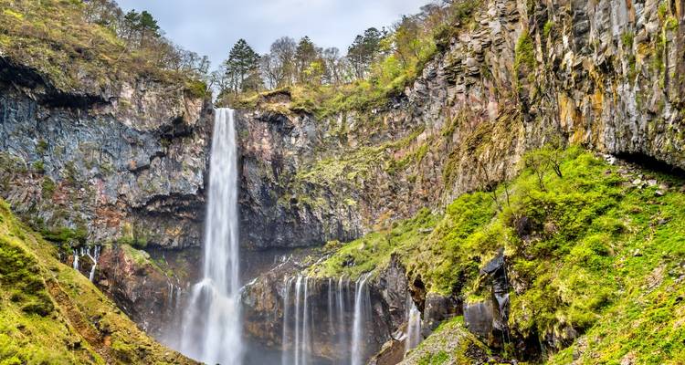 Les puissantes chutes de Kegon se précipitant le long d'une falaise rocheuse entourée de la végétation printanière