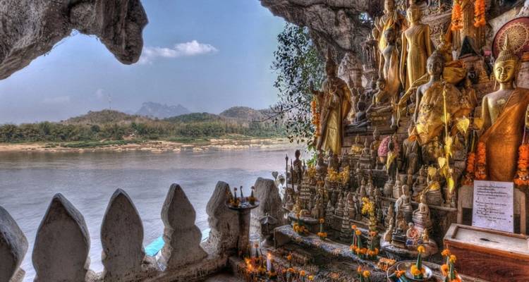 Dutzende goldener Buddhastatuen säumen einen Schrein an einer Felswand, der den Mekong-Fluss bei den Pak-Ou-Höhlen überblickt.