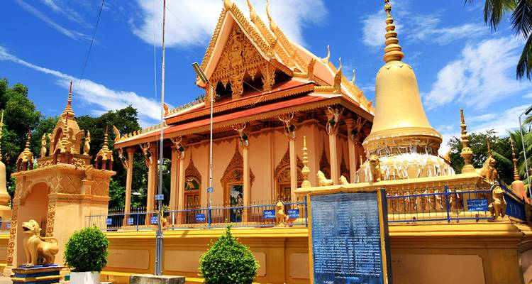 Golden pagoda and stupa set against a vivid blue sky and lush trees.