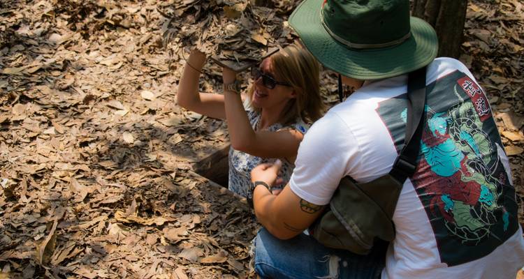 Touristen erkunden ein bewaldetes Gebiet mit laubbedecktem Boden.