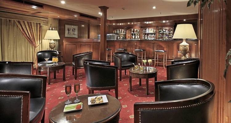 Das Innere einer Lounge-Bar mit mehreren Stühlen und Tischen auf einem rot teppichbelegten Boden.