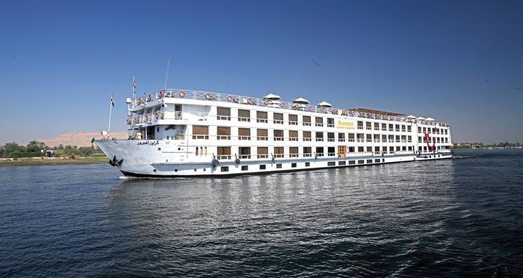 Ein Kreuzfahrtschiff, das auf dem Nil fährt, mit Bergen, die im Hintergrund sichtbar sind.