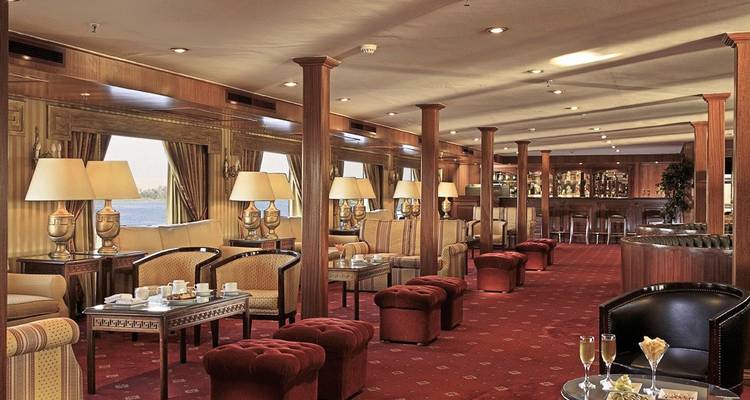 Ein eleganter Loungebereich auf einem Kreuzfahrtschiff mit luxuriösen Sitzgelegenheiten und kleinen Tischen.