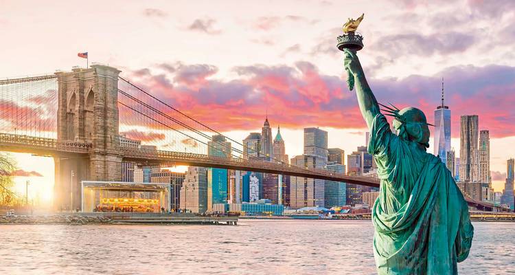 Vrijheidsbeeld met Brooklyn Bridge en stadshorizon bij zonsondergang.