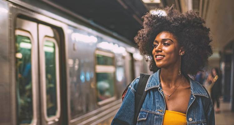 Femme debout dans une station de métro à côté d'un train.
