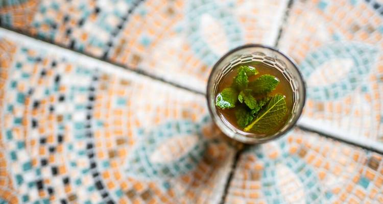 Glas munthee op een oppervlak met mozaïekpatroon.