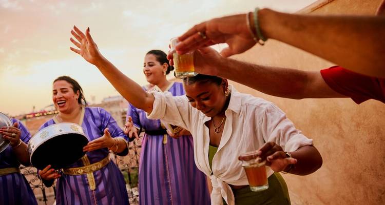Groep vrouwen die met muziek en drankjes vieren op een terras.