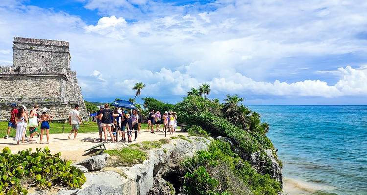 Besucher erkunden antike Ruinen am Meer.