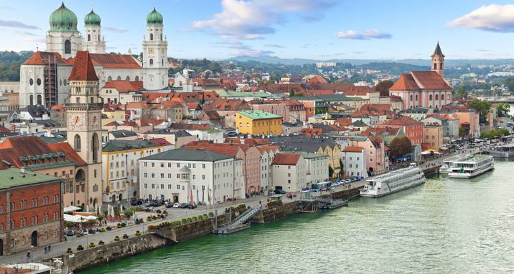 Panoramic view of a city with a river and historic buildings.