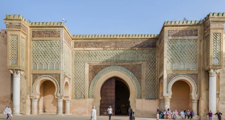 Großes verziertes Tor in der Stadt mit Menschen davor.