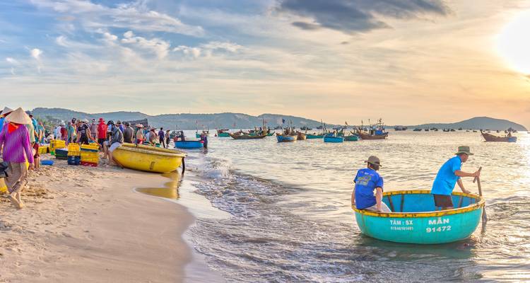 Vissers in ronde boten op een strand bij zonsopgang.