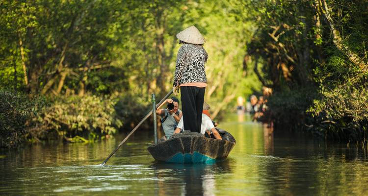 Touristen in einem Boot, die durch einen schmalen Kanal paddeln.