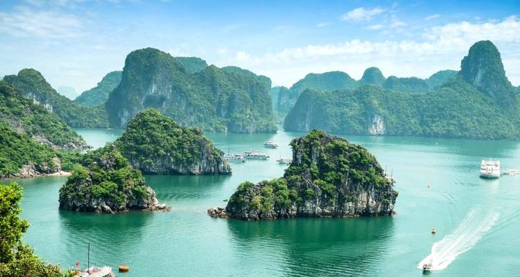 Scenic panorama of emerald islets and calm sea with distant cruise ships in Halong Bay.