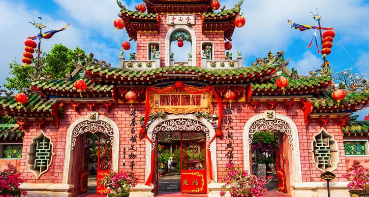 Vibrant pink Chinese assembly hall adorned with lanterns and intricate carvings in Hoi An.