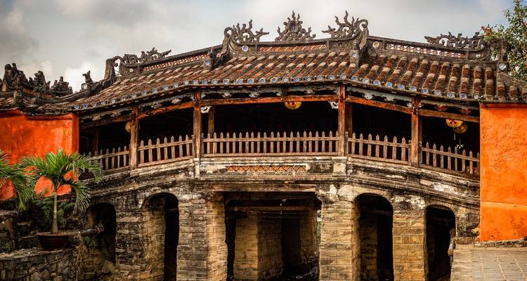 Historic Japanese Covered Bridge with ornate roof tiles and weathered stone piers in Hoi An.