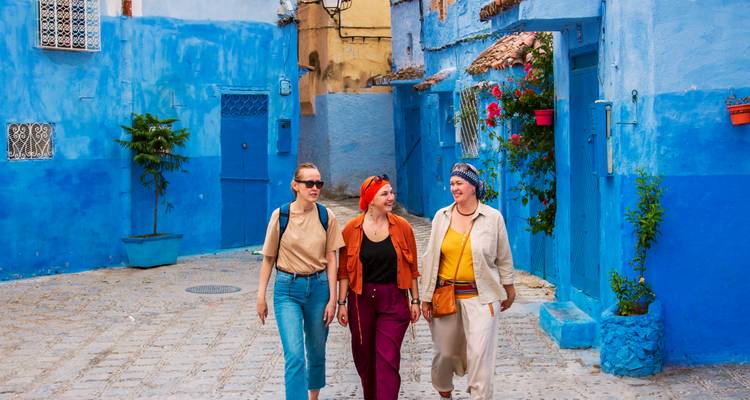 Trois personnes marchant dans une rue peinte en bleu.
