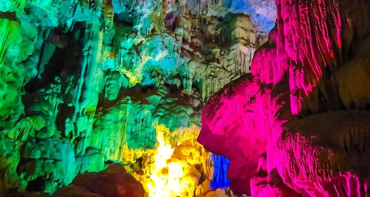 Bunt beleuchteter Höhleninnenraum mit Stalaktiten.