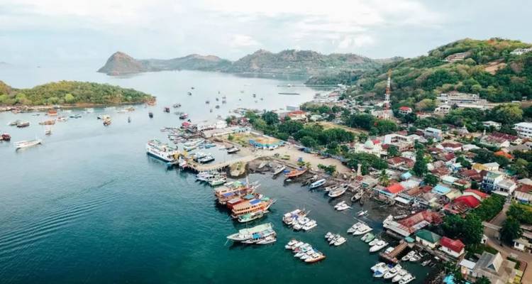 Luftaufnahme des Hafens von Labuan Bajo mit Booten, grünen Hügeln und verstreuten Inseln