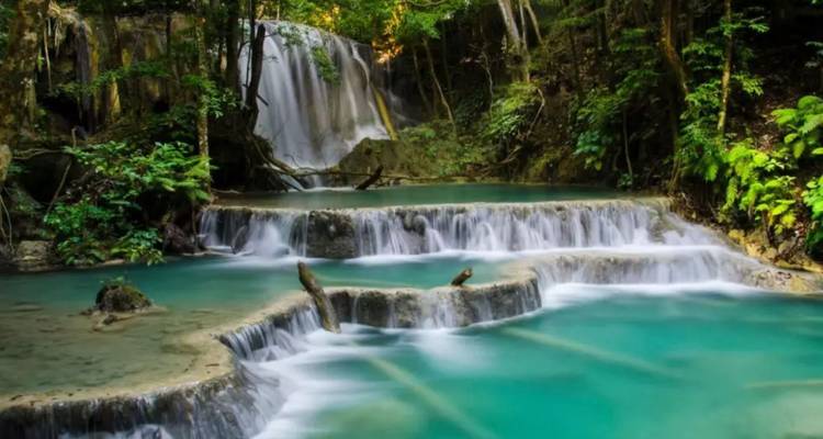 Gestufter Dschungelwasserfall, der in lebhafte türkisfarbene Becken stürzt, umgeben von üppigem Wald