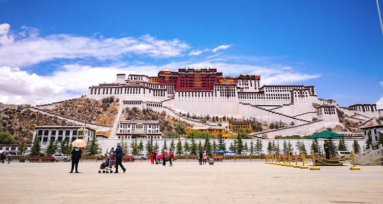 El majestuoso Palacio de Potala se alza sobre la plaza de Lhasa bajo un profundo cielo azul himalayo mientras los visitantes pasean abajo.