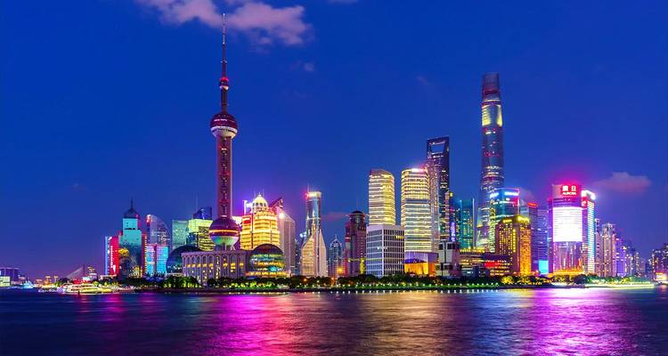 El horizonte de neón de Shanghai brilla sobre el río Huangpu por la noche, destacado por la Torre de la Perla Oriental.
