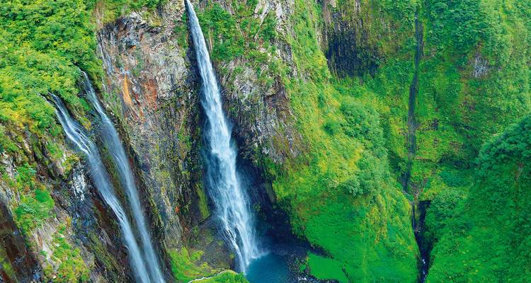 Les hautes et fines cascades s'écoulent le long des parois verdoyantes du canyon dans une piscine turquoise bien en dessous.