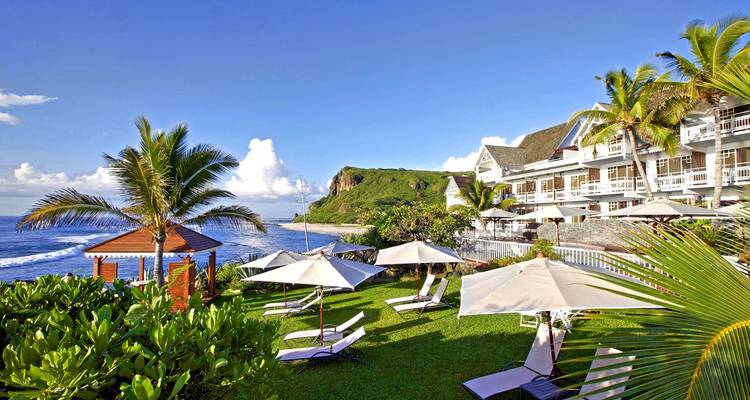 Seaside hotel with palm trees and sun loungers.