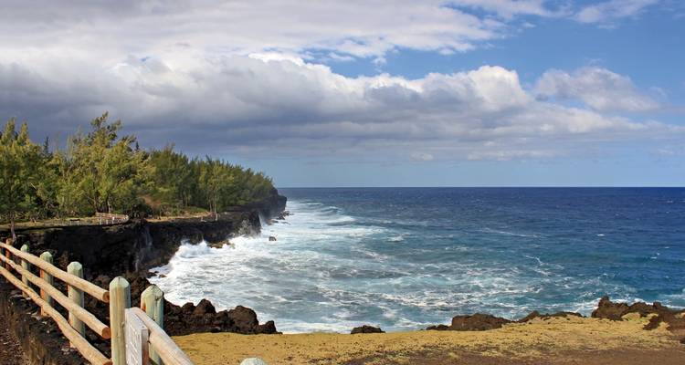 Côte rocheuse avec des vagues qui se brisent et un ciel bleu.
