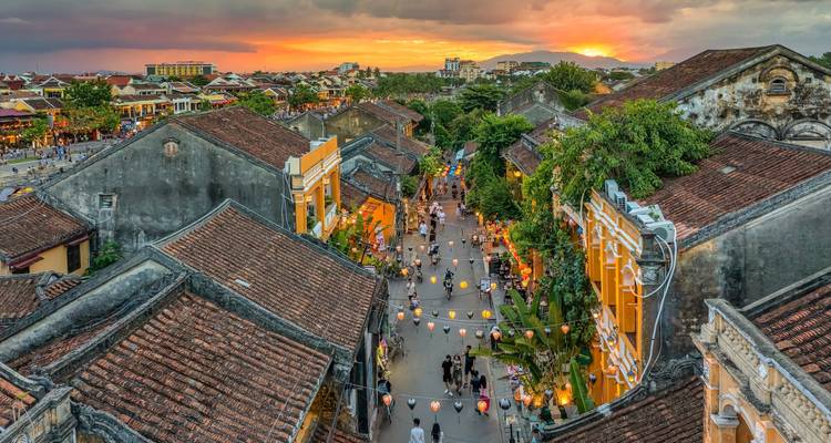 Kleurrijke huizen aan een met lantaarns verlichte straat in Hoi An bij zonsondergang.