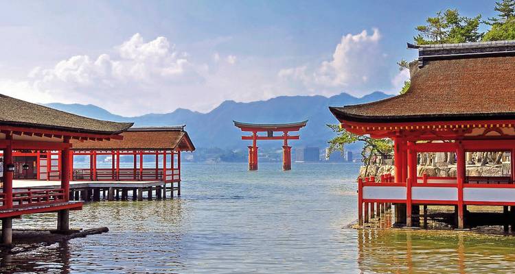 Traditioneller japanischer Schrein über dem Wasser mit Bergen in der Ferne.