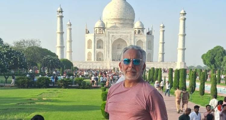 Une personne debout devant le Taj Mahal avec une foule en arrière-plan.