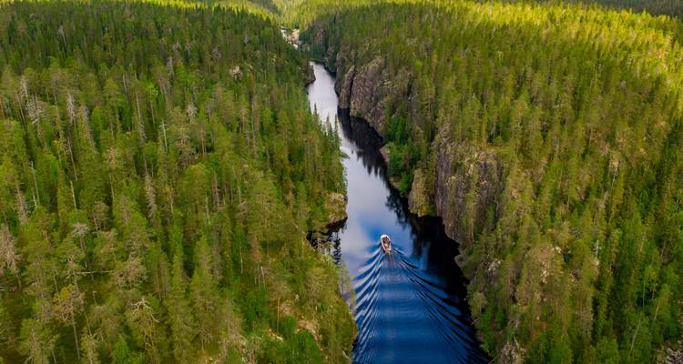 A boat making its way through a narrow river with cliffs.