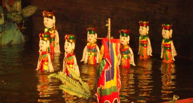 Spectacle traditionnel de marionnettes sur l'eau vietnamiennes avec des figurines en bois aux couleurs vives dansant sur l'eau.