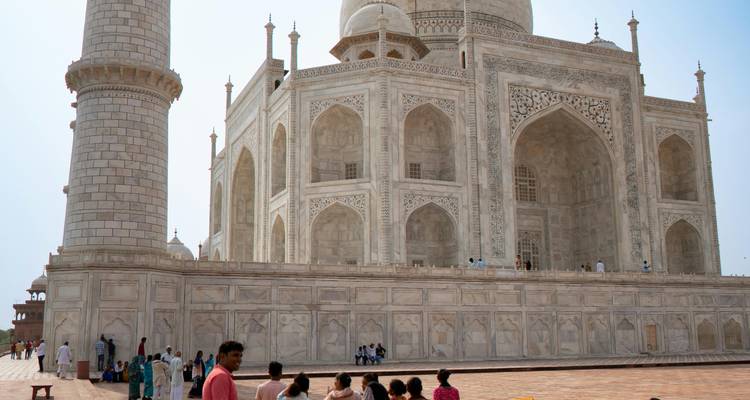 Taj Mahal avec des touristes environnants contre un ciel bleu.