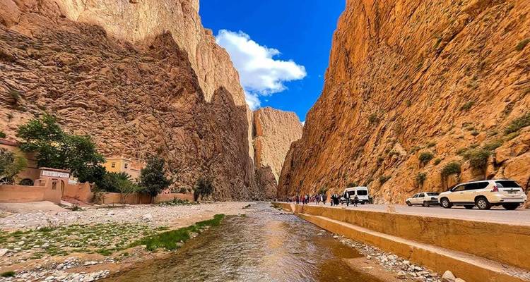 A scenic gorge with a river and vehicles.