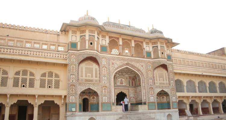 Visitors exploring an intricately decorated palace with arches.