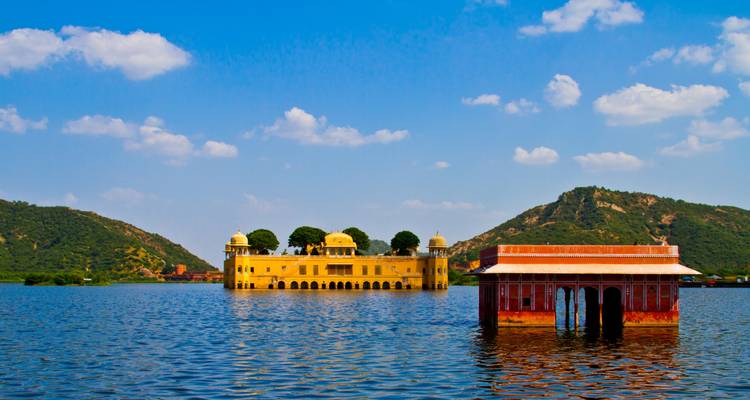 The Jal Mahal situated in the middle of a lake with hills in the background.
