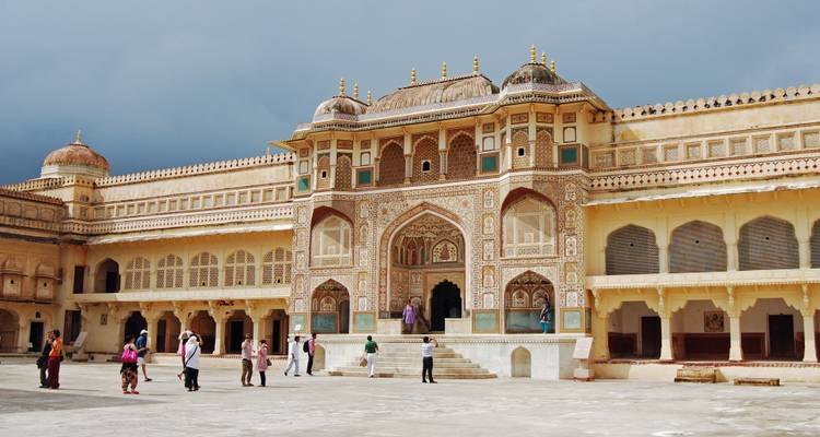 Tourists at the entrance of a historic fort with detailed decoration.