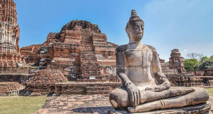 Estatua de Buda de piedra sentada entre las ruinas de ladrillo de Wat Mahathat en Ayutthaya