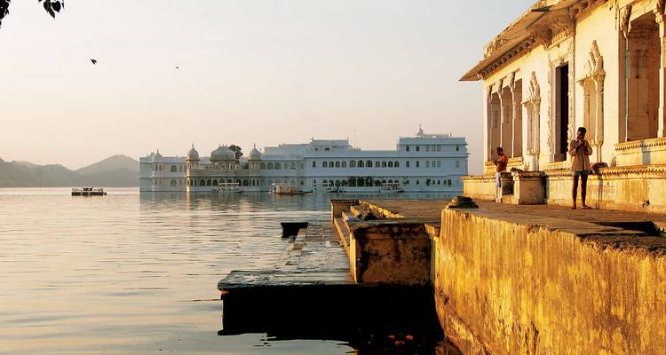 Ein Blick auf den Seepalast in Udaipur mit Menschen, die am Seeufer stehen.