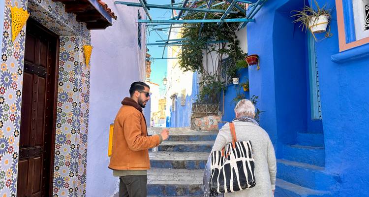 Two people exploring a blue-painted street in Chefchaouen.