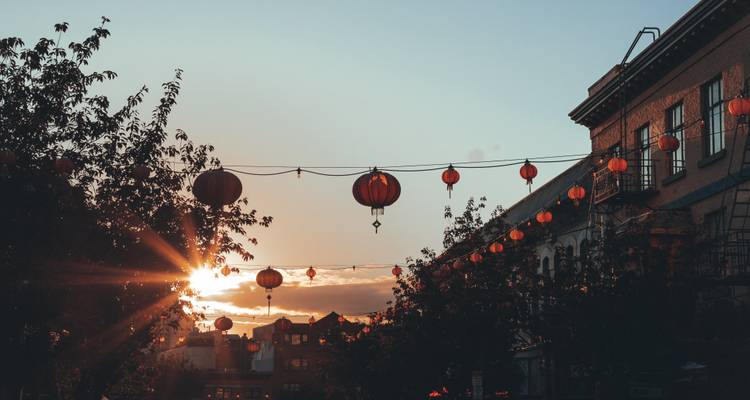 Slingers rode lantaarns verlichten een historische straat bij zonsondergang en creëren een warme feestelijke sfeer.